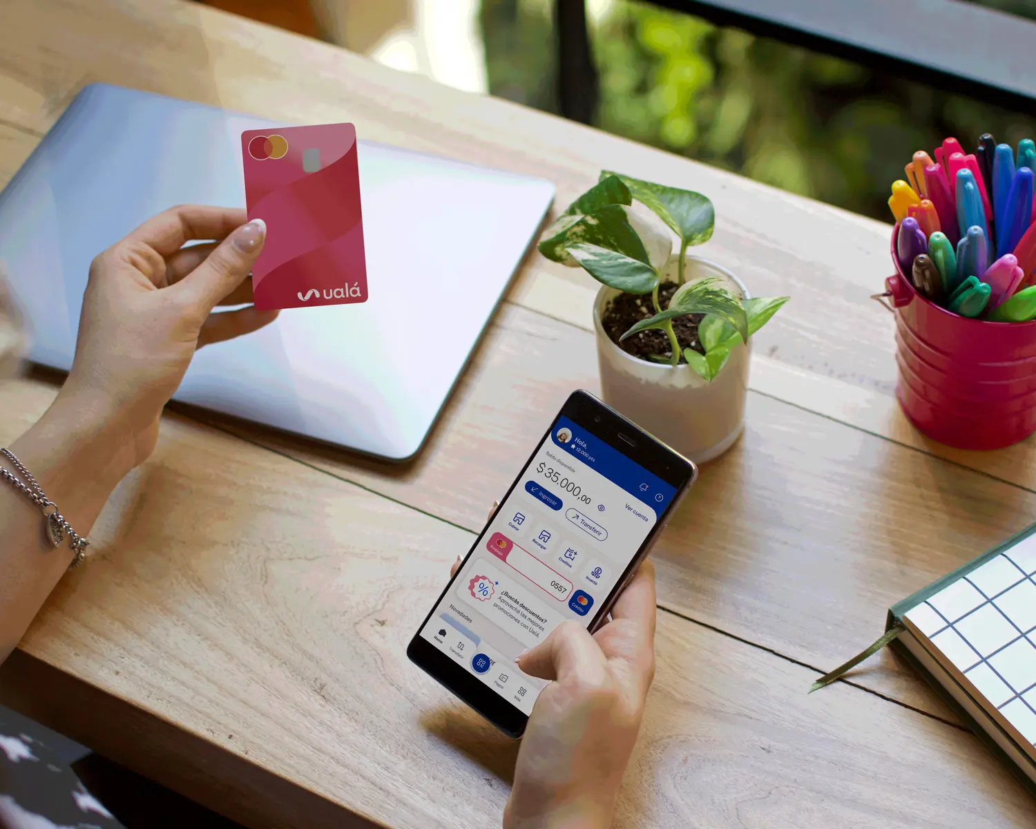 Persona sosteniendo la tarjeta prepaga Ualá y app de Ualá.