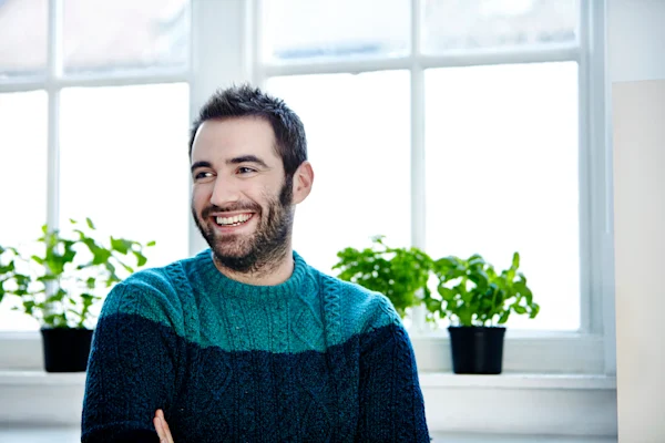 Smiling Guy In Sweater Sitting Down Indoors