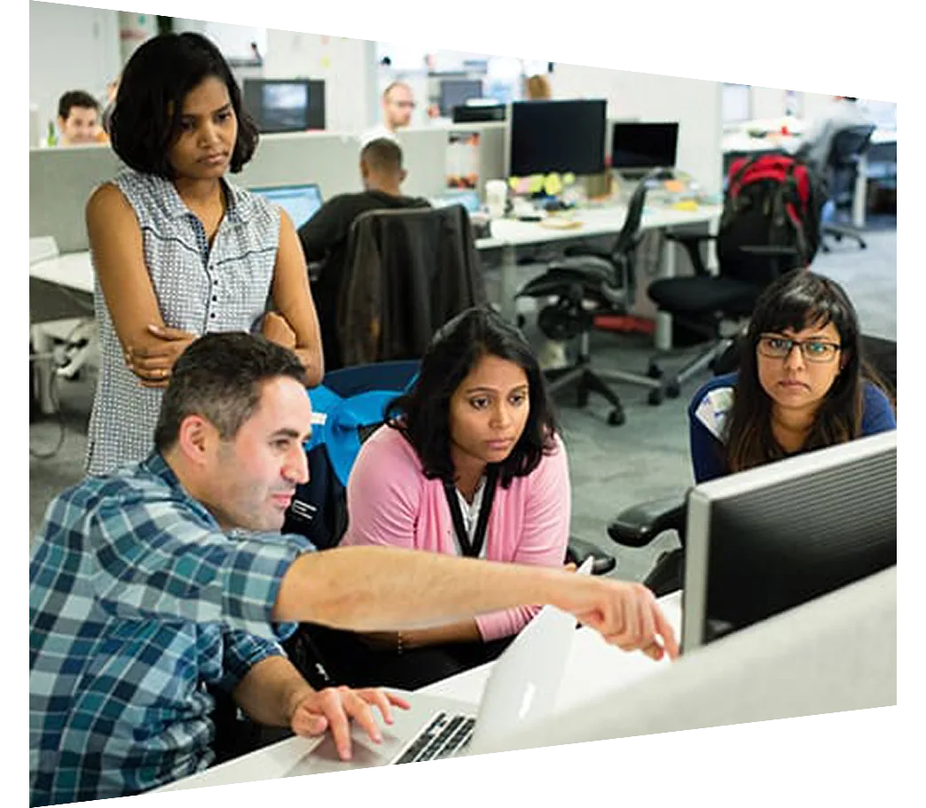 Group of colleagues sitting at a desk looking at a monitor