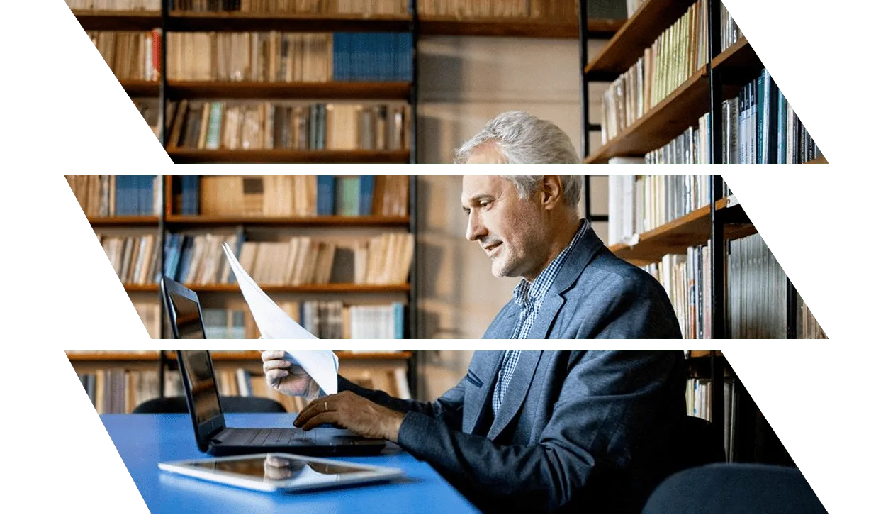 Mature man in suit working at desk in library