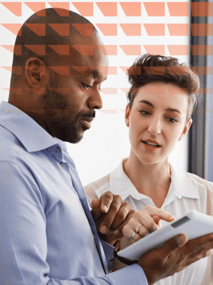 Man and woman engaged in discussion while looking at a tablet together.