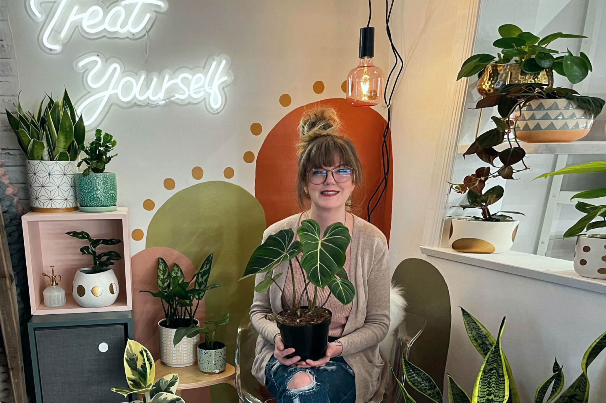 Woman sitting in chair, holding a plant. 